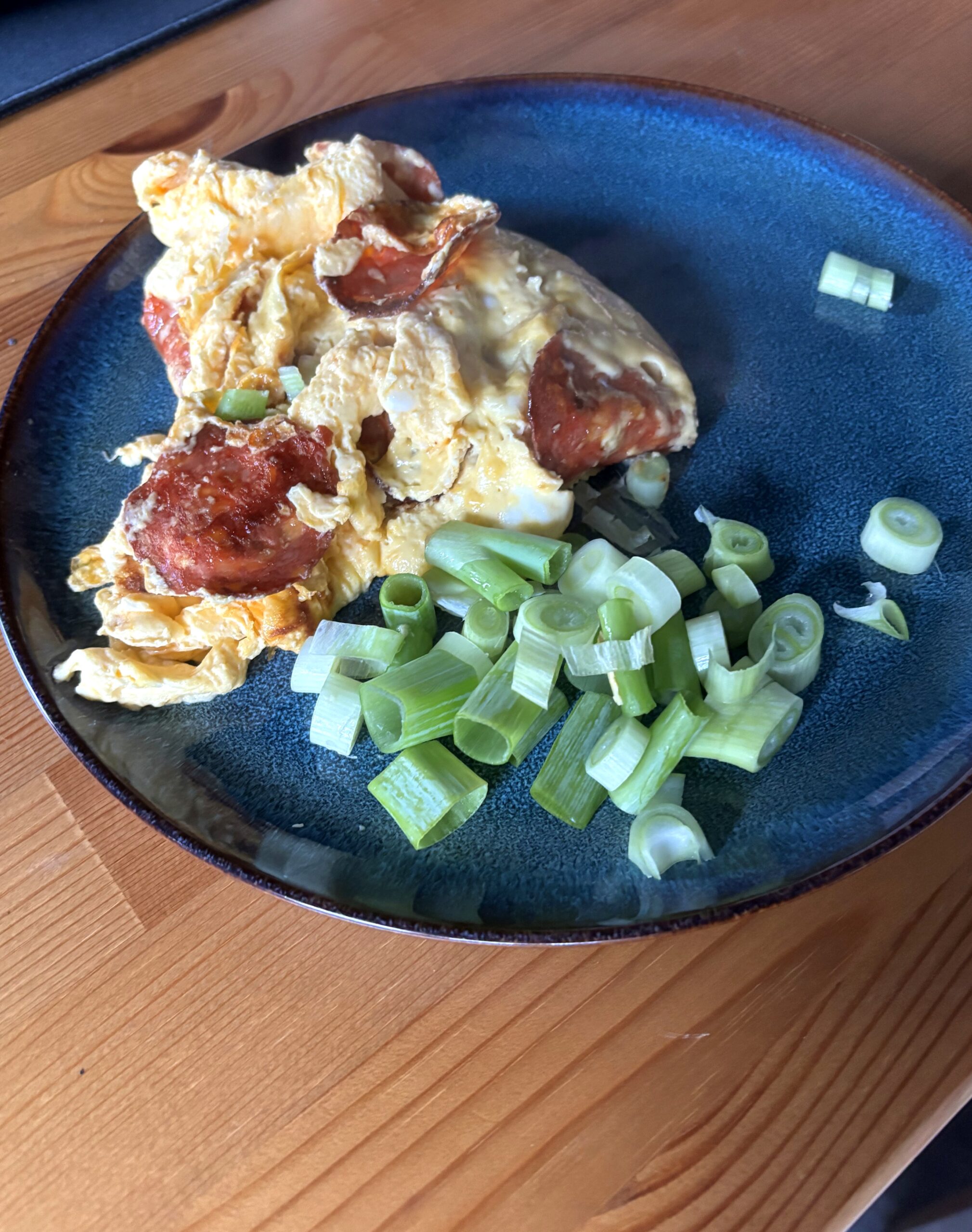 Eggerøre med chorizo og vårløk på mørk tallerken