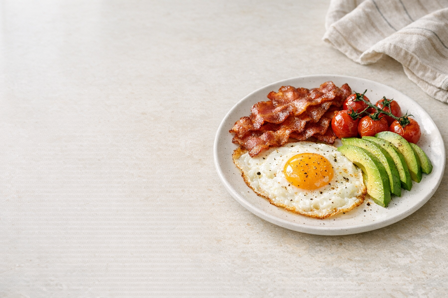 Tallerken med egg, avokado, bacon og tomater