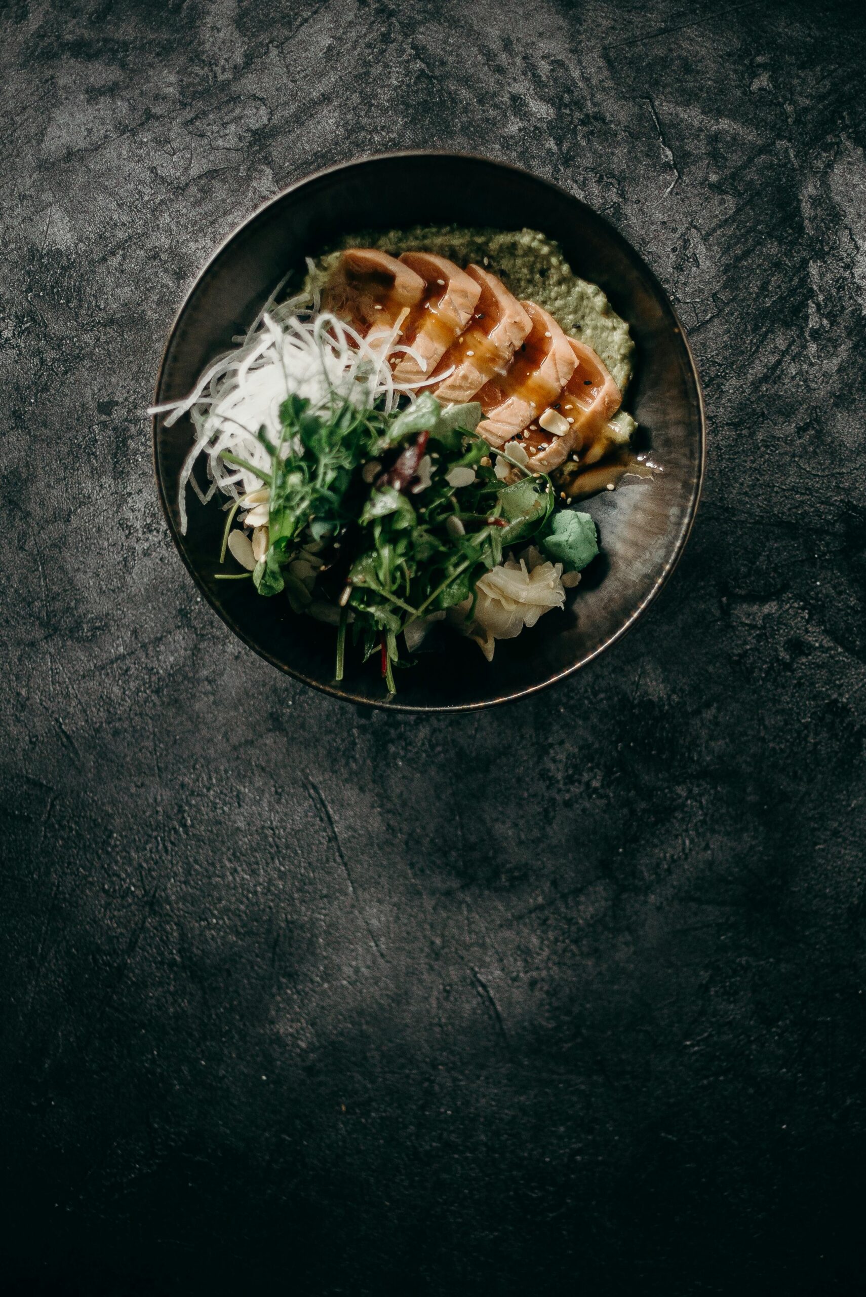 Mørk skål med laks, grønt og blomkålris